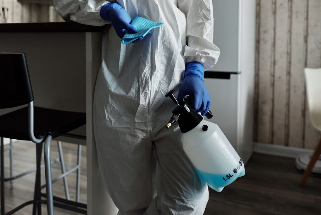 Technicien en combinaison de protection, pulvérisateur et lingette à la main